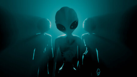 Grey alien extraterrestrial in dark black room, looking at viewer